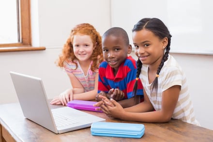 Three children sharing computer at elementary school.